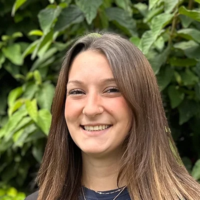Orthodontic Assistant Kacey Smiling In Front Of A Hedge