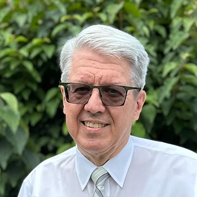 Orthodontist George Walker Smiling In Front Of A Hedge